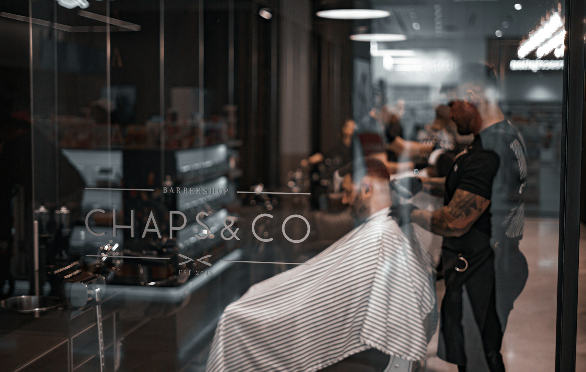 Interior barbershop premium dengan beberapa kursi dan barber yang bekerja